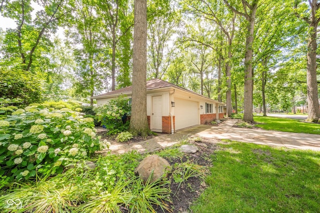 2613 W Queensbury Rd, Muncie, IN 47304 - view of side of home with brick siding, concrete driveway, a garage, and a lawn