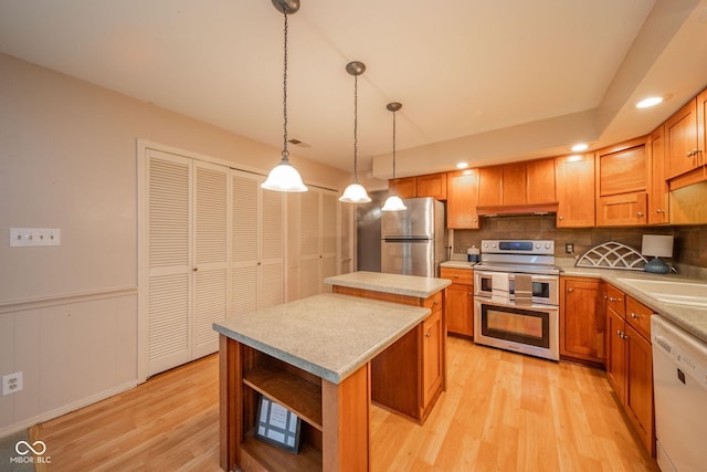 2613 W Queensbury Rd, Muncie, IN 47304 - kitchen featuring appliances with stainless steel finishes, a kitchen island, light wood-type flooring, under cabinet range hood, and decorative backsplash