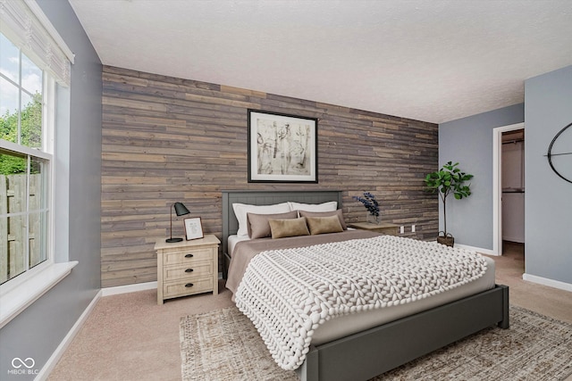 16629 Greensboro Dr, Westfield, IN 46074 - bedroom with an accent wall, wooden walls, light colored carpet, a textured ceiling, and a walk in closet