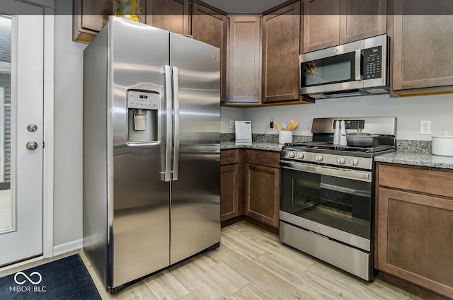 3933 Wren Dr, Brownsburg, IN 46112 - kitchen featuring appliances with stainless steel finishes, light stone counters, light wood finished floors, and dark brown cabinetry