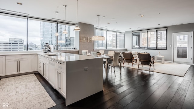 225 N New Jersey St Unit 52, Indianapolis, IN 46204 - kitchen with dark wood-style floors, white cabinetry, open floor plan, decorative light fixtures, and a peninsula