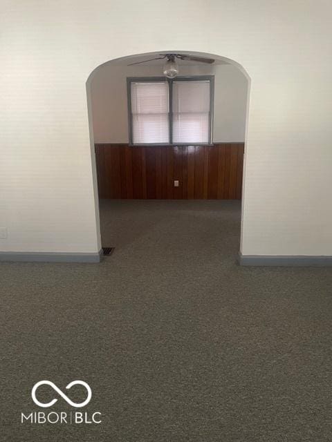 416 W 21st St, Anderson, IN 46016 - carpeted empty room with arched walkways, wood walls, and wainscoting
