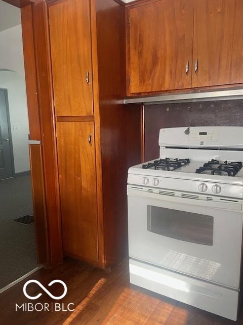 416 W 21st St, Anderson, IN 46016 - kitchen with white gas range oven, brown cabinets, arched walkways, and exhaust hood