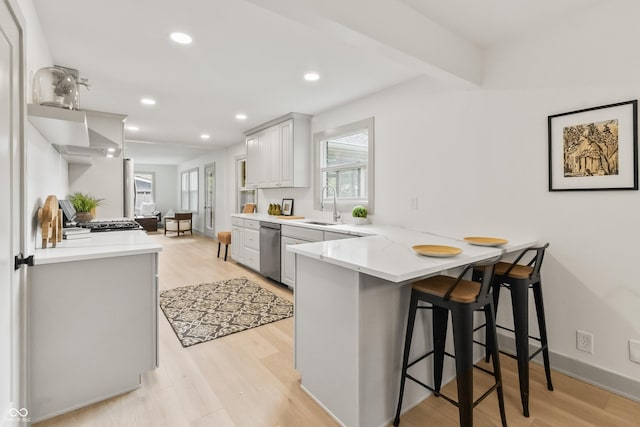 8246 Windcombe Blvd, Indianapolis, IN 46240 - kitchen with a peninsula, stainless steel dishwasher, a breakfast bar area, light wood-style floors, and recessed lighting