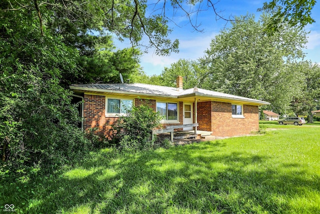 10159 Hodge Rd, Clayton, IN 46118 - rear view of house featuring brick siding, a lawn, a chimney, and a metal roof