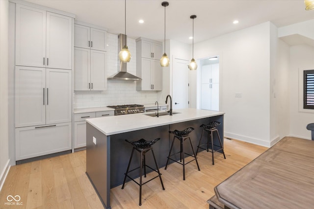 1905 N Alabama St, Indianapolis, IN 46202 - kitchen featuring wall chimney exhaust hood, light wood-style flooring, backsplash, a kitchen breakfast bar, and stainless steel gas range