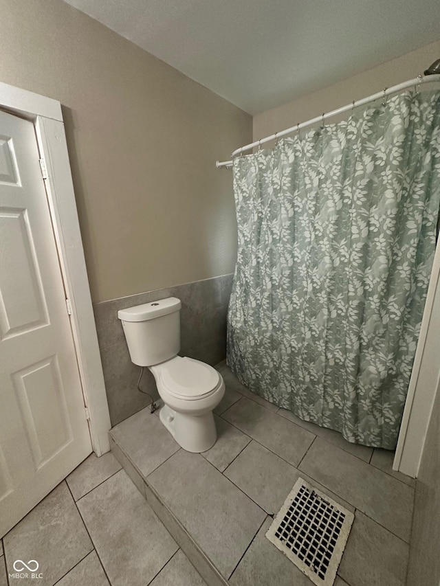 1810 N Parker Ave, Indianapolis, IN 46218 - bathroom featuring wainscoting, tile walls, tile patterned floors, and a shower with curtain