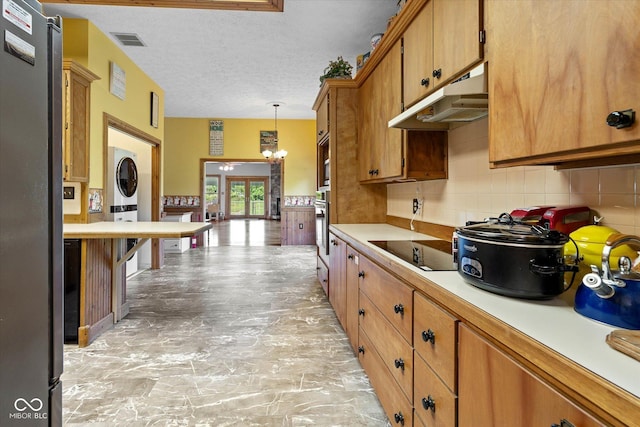 7516 S County Road 300 W, Clayton, IN 46118 - kitchen with estacked washer and dryer, appliances with stainless steel finishes, light countertops, a chandelier, and brown cabinets