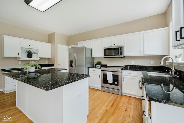12490 Windbush Way, Carmel, IN 46033 - kitchen with stainless steel appliances, light wood-style flooring, white cabinets, dark stone countertops, and a kitchen island