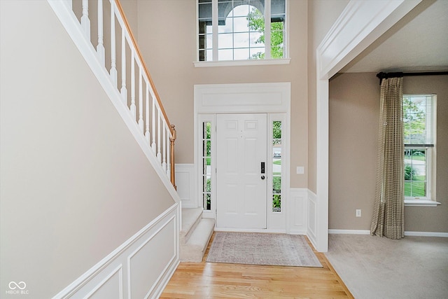 12490 Windbush Way, Carmel, IN 46033 - foyer entrance featuring plenty of natural light, a decorative wall, light wood-style floors, stairway, and wainscoting