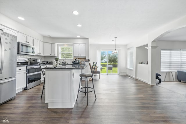 2463 Kettering Way, Indianapolis, IN 46214 - kitchen featuring appliances with stainless steel finishes, dark countertops, a breakfast bar, plenty of natural light, and recessed lighting