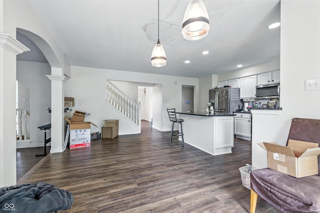 2463 Kettering Way, Indianapolis, IN 46214 - kitchen with appliances with stainless steel finishes, open floor plan, ornate columns, dark countertops, and white cabinetry