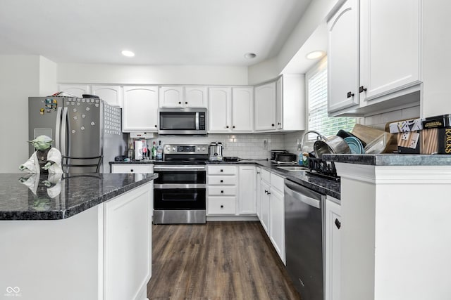 2463 Kettering Way, Indianapolis, IN 46214 - kitchen featuring appliances with stainless steel finishes, dark wood-style flooring, white cabinetry, decorative backsplash, and dark stone counters