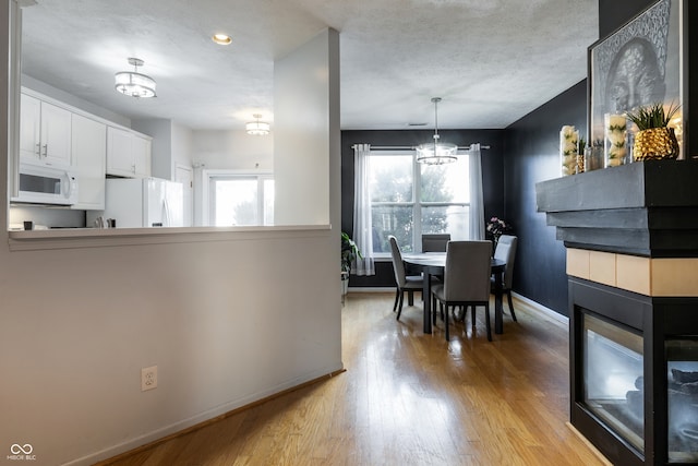 9525 Longwell Dr, Indianapolis, IN 46240 - dining area with a chandelier, light wood finished floors, a multi sided fireplace, plenty of natural light, and a textured ceiling