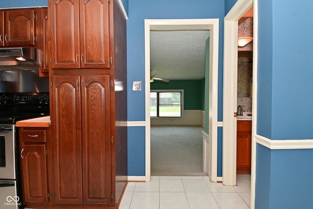 136 W Loretta Dr, Indianapolis, IN 46217 - kitchen with range hood, stainless steel electric range oven, light tile patterned floors, light carpet, and a textured ceiling