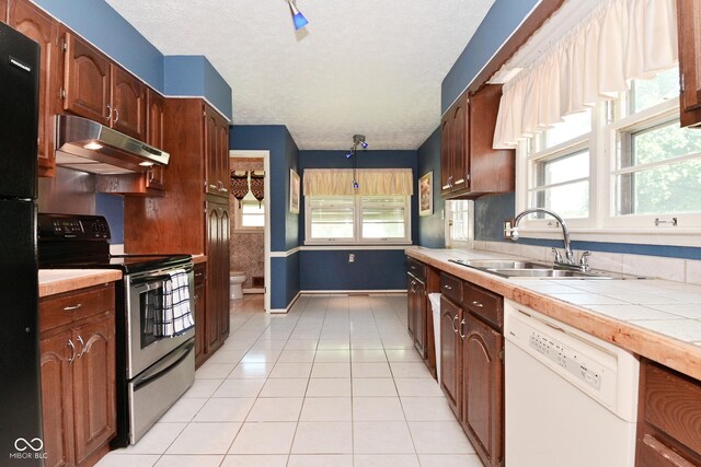 136 W Loretta Dr, Indianapolis, IN 46217 - kitchen with stainless steel electric range oven, white dishwasher, under cabinet range hood, light tile patterned flooring, and freestanding refrigerator