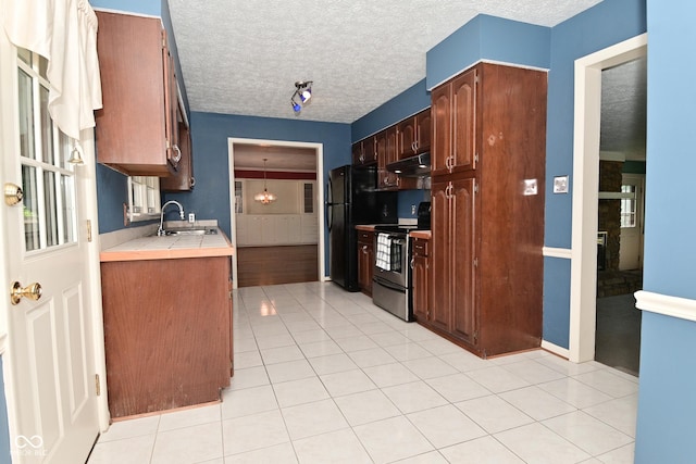 136 W Loretta Dr, Indianapolis, IN 46217 - kitchen with electric stove, under cabinet range hood, a textured ceiling, freestanding refrigerator, and light tile patterned flooring