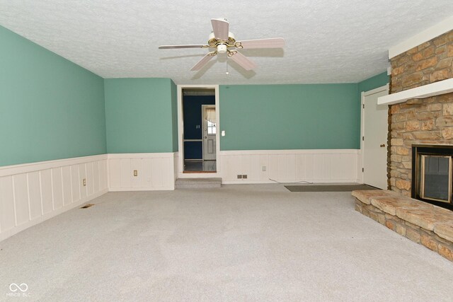 136 W Loretta Dr, Indianapolis, IN 46217 - unfurnished living room featuring a fireplace, a textured ceiling, wainscoting, carpet, and a ceiling fan