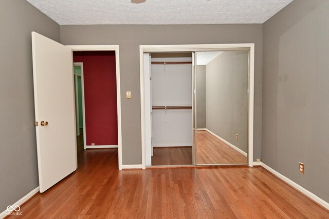 136 W Loretta Dr, Indianapolis, IN 46217 - unfurnished bedroom featuring wood finished floors, a textured ceiling, and a closet
