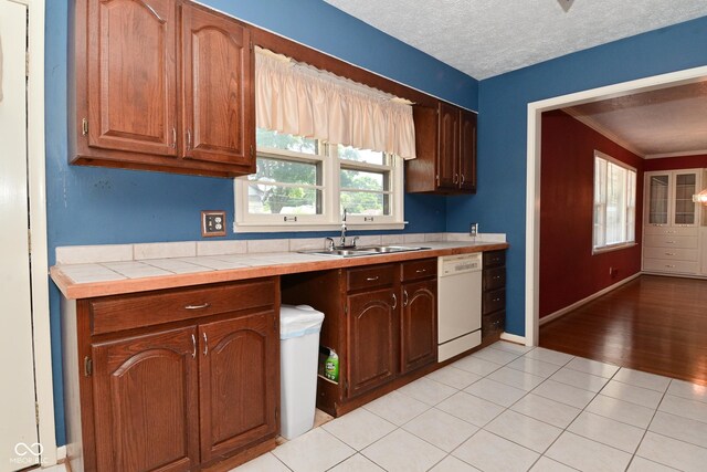 136 W Loretta Dr, Indianapolis, IN 46217 - kitchen with dishwasher, tile counters, crown molding, light tile patterned flooring, and a textured ceiling