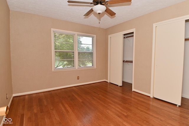 136 W Loretta Dr, Indianapolis, IN 46217 - unfurnished bedroom featuring wood finished floors, multiple closets, a ceiling fan, and a textured ceiling