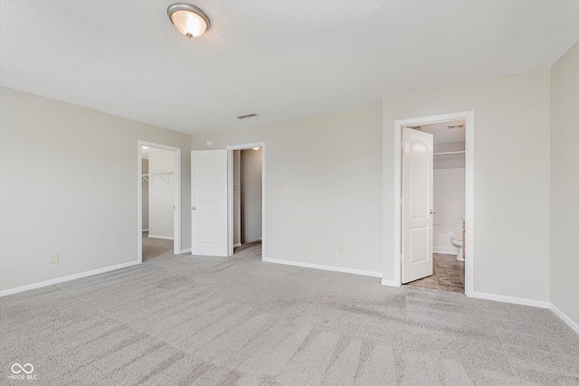 7572 Wymm Ln, Ingalls, IN 46048 - unfurnished bedroom featuring a spacious closet, carpet, connected bathroom, a closet, and a textured ceiling