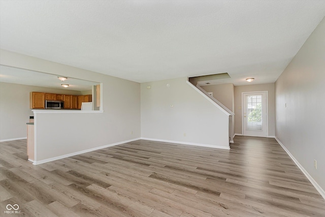 7572 Wymm Ln, Ingalls, IN 46048 - unfurnished living room featuring light wood-type flooring and stairs
