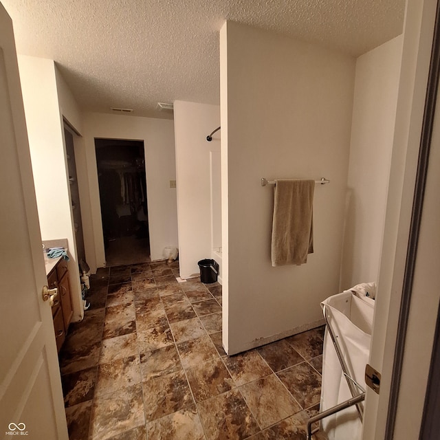 10775 Cyrus Dr, Indianapolis, IN 46231 - full bath with vanity, a shower, a textured ceiling, and stone finish flooring