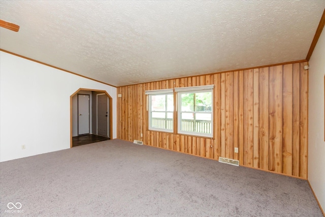305 Pike St, Darlington, IN 47940 - carpeted spare room with a textured ceiling, arched walkways, wood walls, and crown molding