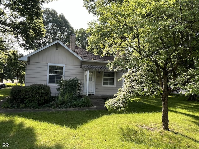 1900 S 25th St, Terre Haute, IN 47802 - view of front of property with a front yard, a chimney, a shingled roof, and board and batten siding