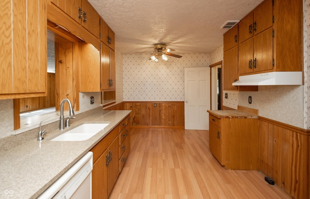 660 E Dr, Seymour, IN 47274 - kitchen with under cabinet range hood, wainscoting, a ceiling fan, brown cabinetry, and light wood-style floors