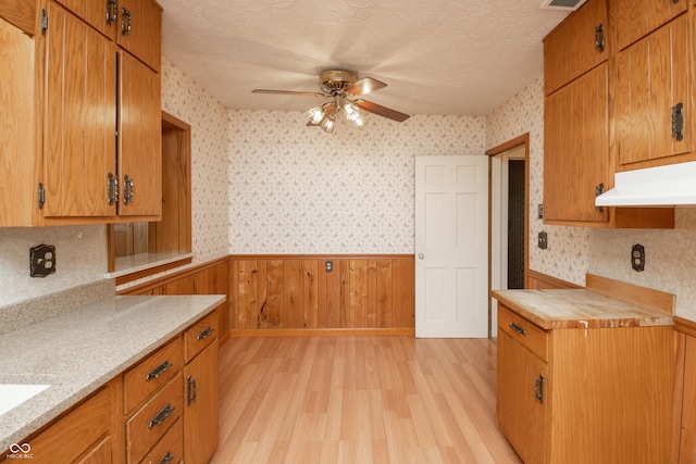660 E Dr, Seymour, IN 47274 - kitchen featuring wallpapered walls, under cabinet range hood, wainscoting, light countertops, and a ceiling fan