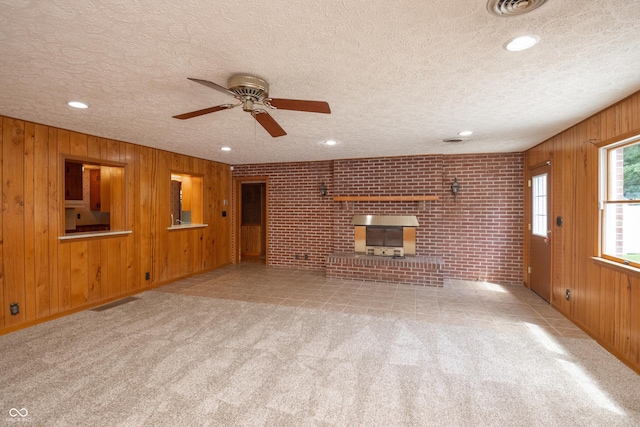 660 E Dr, Seymour, IN 47274 - unfurnished living room featuring wood walls, a fireplace, ceiling fan, carpet floors, and a textured ceiling