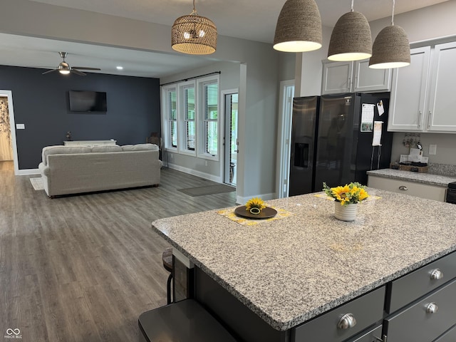 188 Gettysburg, Coatesville, IN 46121 - kitchen with black fridge with ice dispenser, a ceiling fan, wood finished floors, light stone countertops, and a center island
