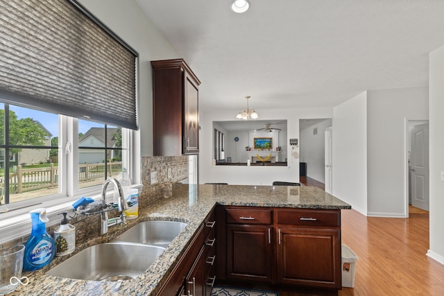 7350 Gold King Way, Indianapolis, IN 46259 - kitchen with a peninsula, light wood-style floors, a chandelier, decorative light fixtures, and stone countertops
