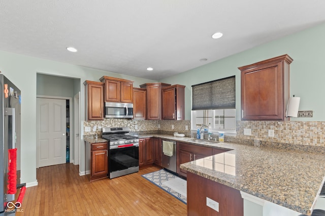 7350 Gold King Way, Indianapolis, IN 46259 - kitchen with appliances with stainless steel finishes, a peninsula, light wood-style floors, tasteful backsplash, and recessed lighting