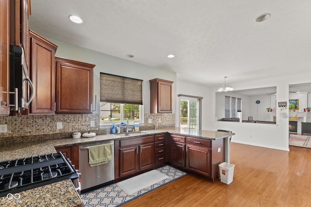 7350 Gold King Way, Indianapolis, IN 46259 - kitchen featuring appliances with stainless steel finishes, backsplash, light wood-style floors, a chandelier, and a peninsula