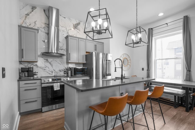 934 Calvary St, Indianapolis, IN 46203 - kitchen featuring stainless steel appliances, gray cabinets, wall chimney range hood, dark countertops, and a chandelier