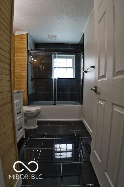 4430 Wexford Rd, Indianapolis, IN 46226 - bathroom with bath / shower combo with glass door, a textured ceiling, and vanity