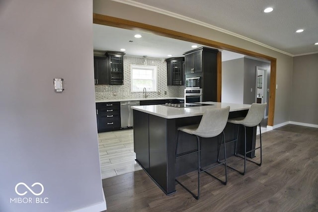 4430 Wexford Rd, Indianapolis, IN 46226 - kitchen featuring stainless steel appliances, wood finished floors, dark cabinetry, backsplash, and light countertops