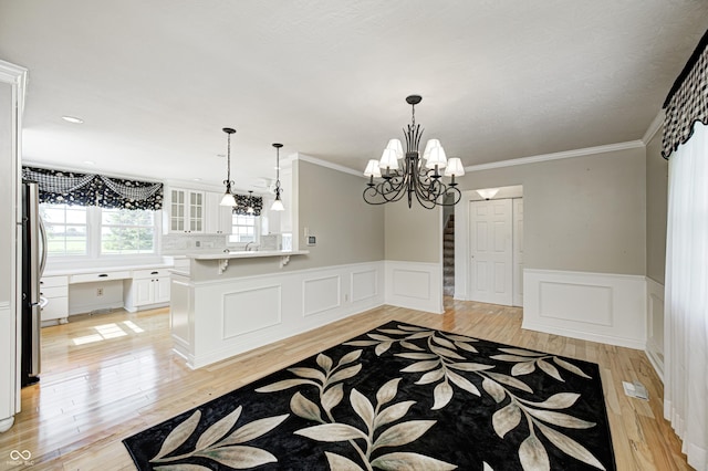 303 E County Road 500 N, Pittsboro, IN 46167 - unfurnished dining area with a wainscoted wall, light wood finished floors, ornamental molding, a chandelier, and a decorative wall