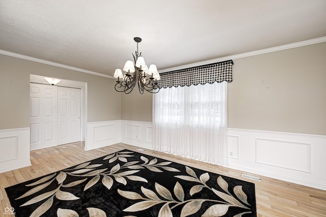 303 E County Road 500 N, Pittsboro, IN 46167 - unfurnished dining area with wood finished floors, a wainscoted wall, a chandelier, crown molding, and a decorative wall