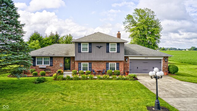 303 E County Road 500 N, Pittsboro, IN 46167 - tri-level home featuring an attached garage, concrete driveway, a chimney, a front yard, and brick siding