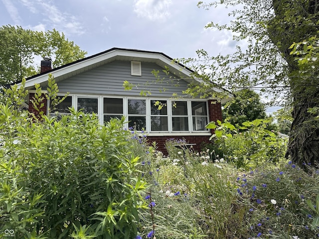 1433 N Colorado Ave, Indianapolis, IN 46201 - view of home's exterior with brick siding, a chimney, and a sunroom