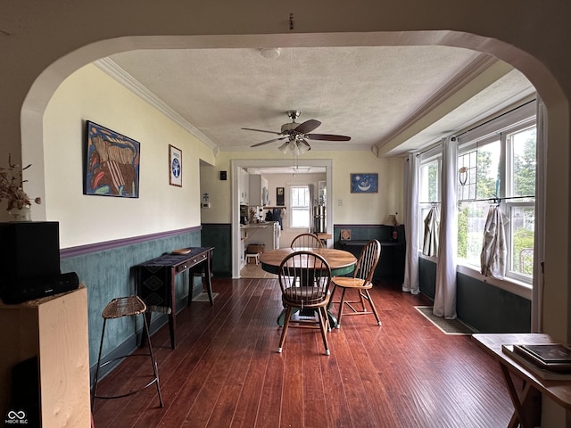 1433 N Colorado Ave, Indianapolis, IN 46201 - dining room with wainscoting, ornamental molding, dark wood-style floors, a ceiling fan, and arched walkways