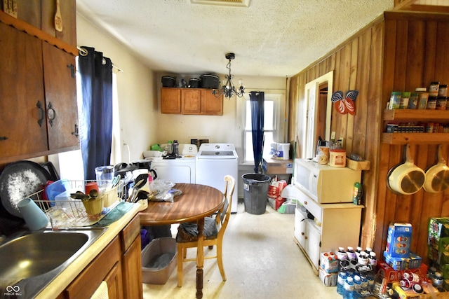 2638 S Mcclure St, Indianapolis, IN 46241 - kitchen with washer and dryer, brown cabinets, a textured ceiling, finished concrete floors, and pendant lighting