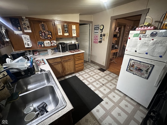 1033 S Locke St, Kokomo, IN 46902 - kitchen featuring light flooring, freestanding refrigerator, stainless steel microwave, light countertops, and brown cabinetry
