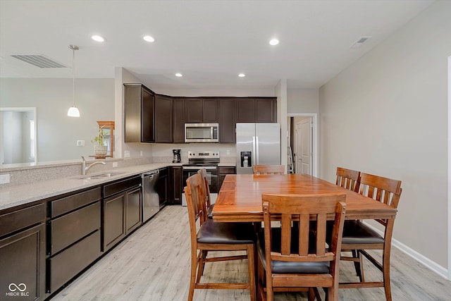 6644 Aberdeen Dr, Mccordsville, IN 46055 - kitchen with appliances with stainless steel finishes, dark brown cabinetry, light wood-style flooring, decorative light fixtures, and recessed lighting