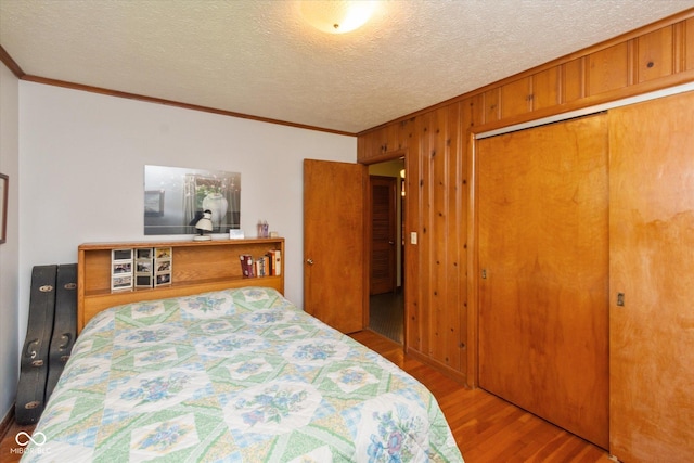 2808 Woodside Dr, Plainfield, IN 46168 - bedroom featuring crown molding, wood finished floors, wooden walls, a closet, and a textured ceiling