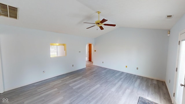 6640 Chipping Ct, Indianapolis, IN 46268 - empty room with a ceiling fan, arched walkways, wood finished floors, and vaulted ceiling